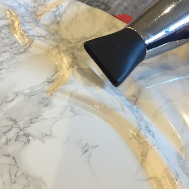Curved surface covered with marble grey vinyl and silver hair dryer in top right corner
