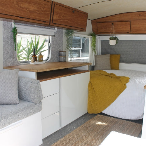 Upcycled caravan with grey chevron marble tiles, white cupboards and grey and mustard decor