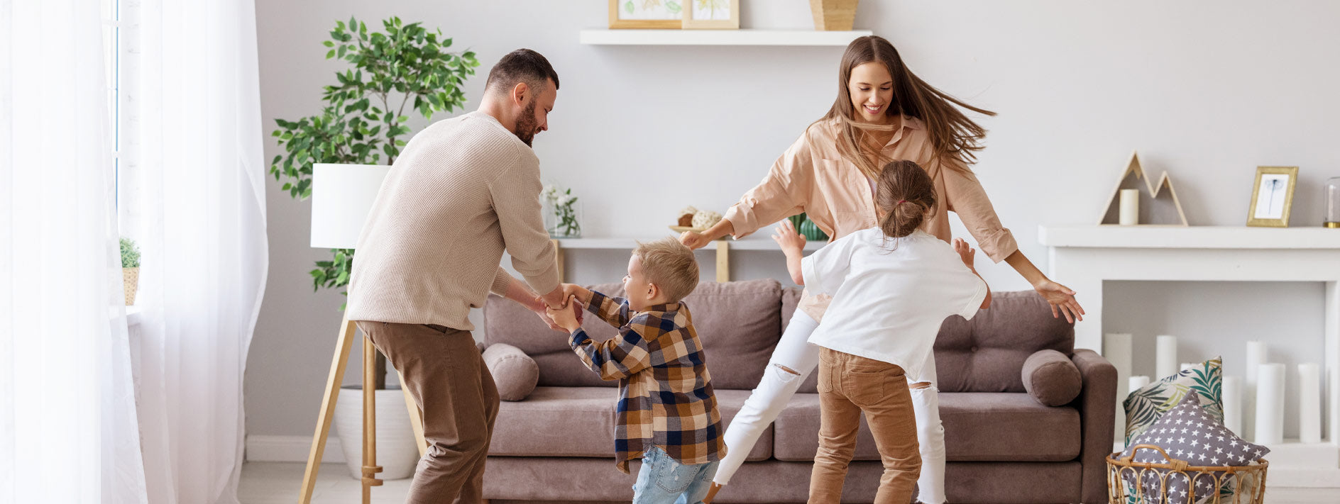 Happy dance by mum, dad and two children in their living room in front of a couch