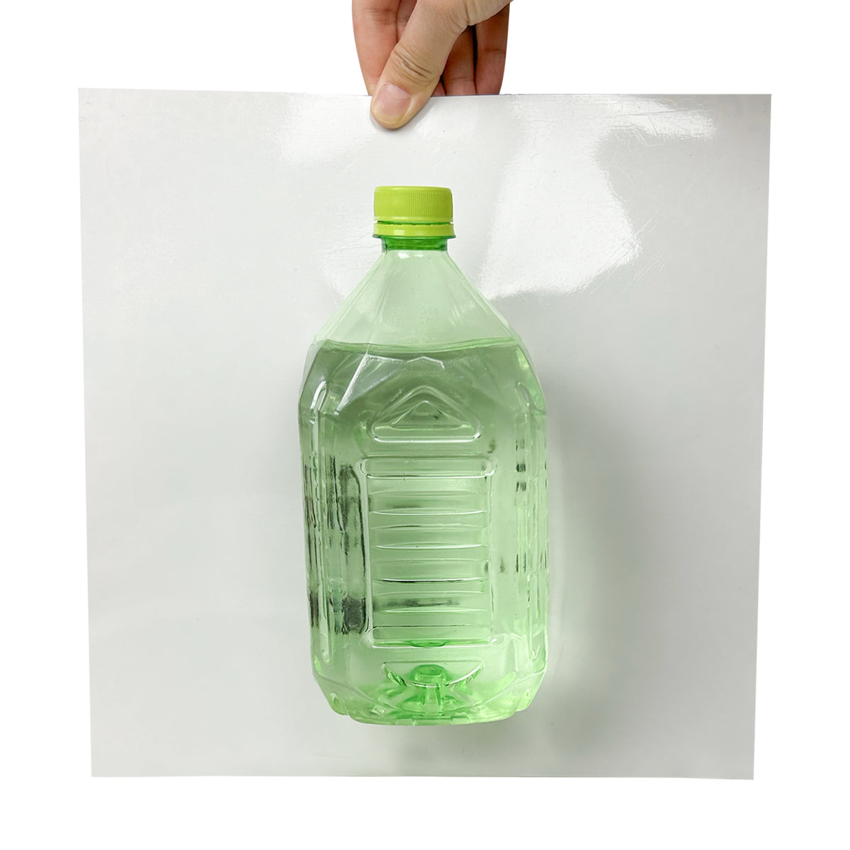 Green bottle with a green cap held by a glue from an adhesive floor tile
