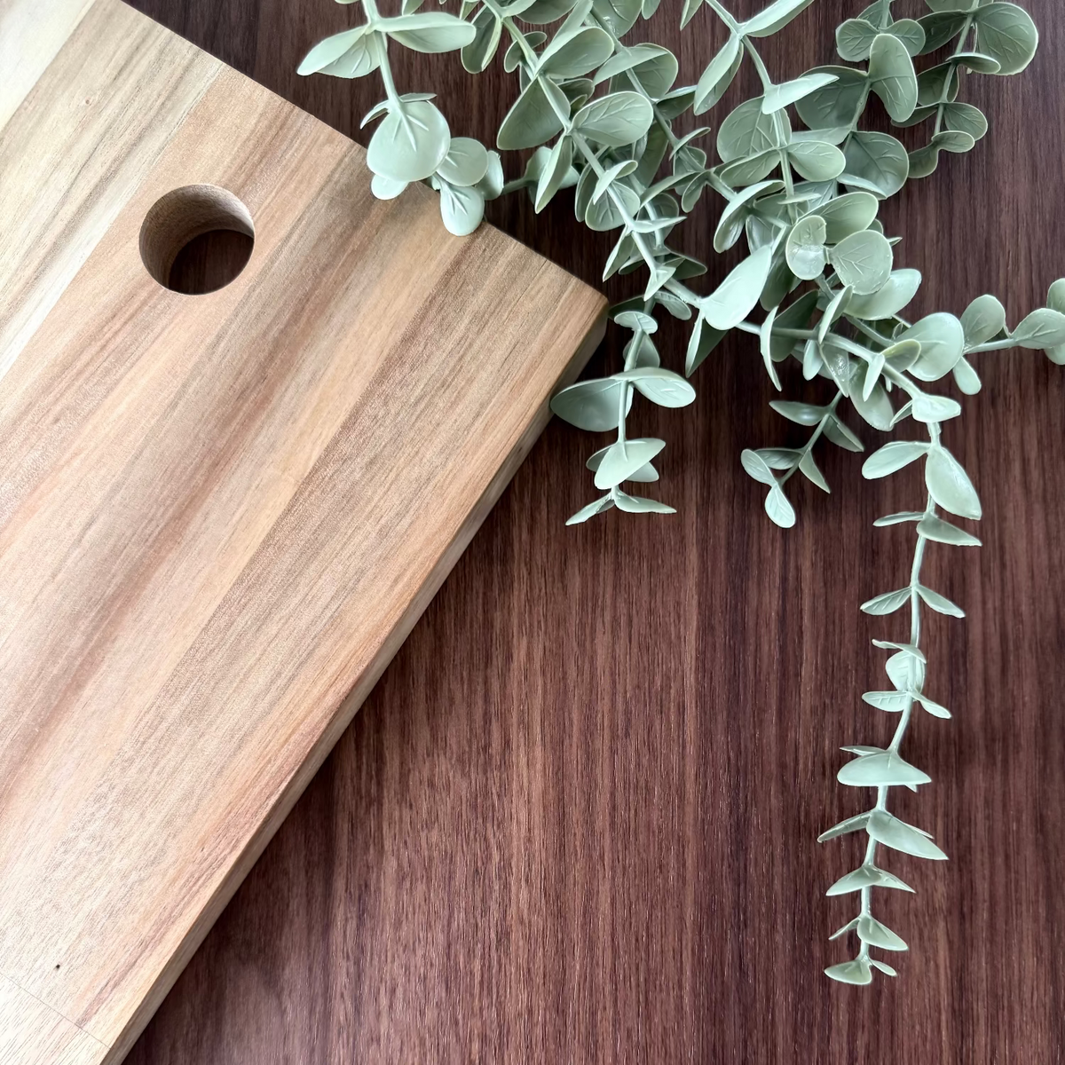 Wooden cutting board with a plant on a walnut vinyl surface
