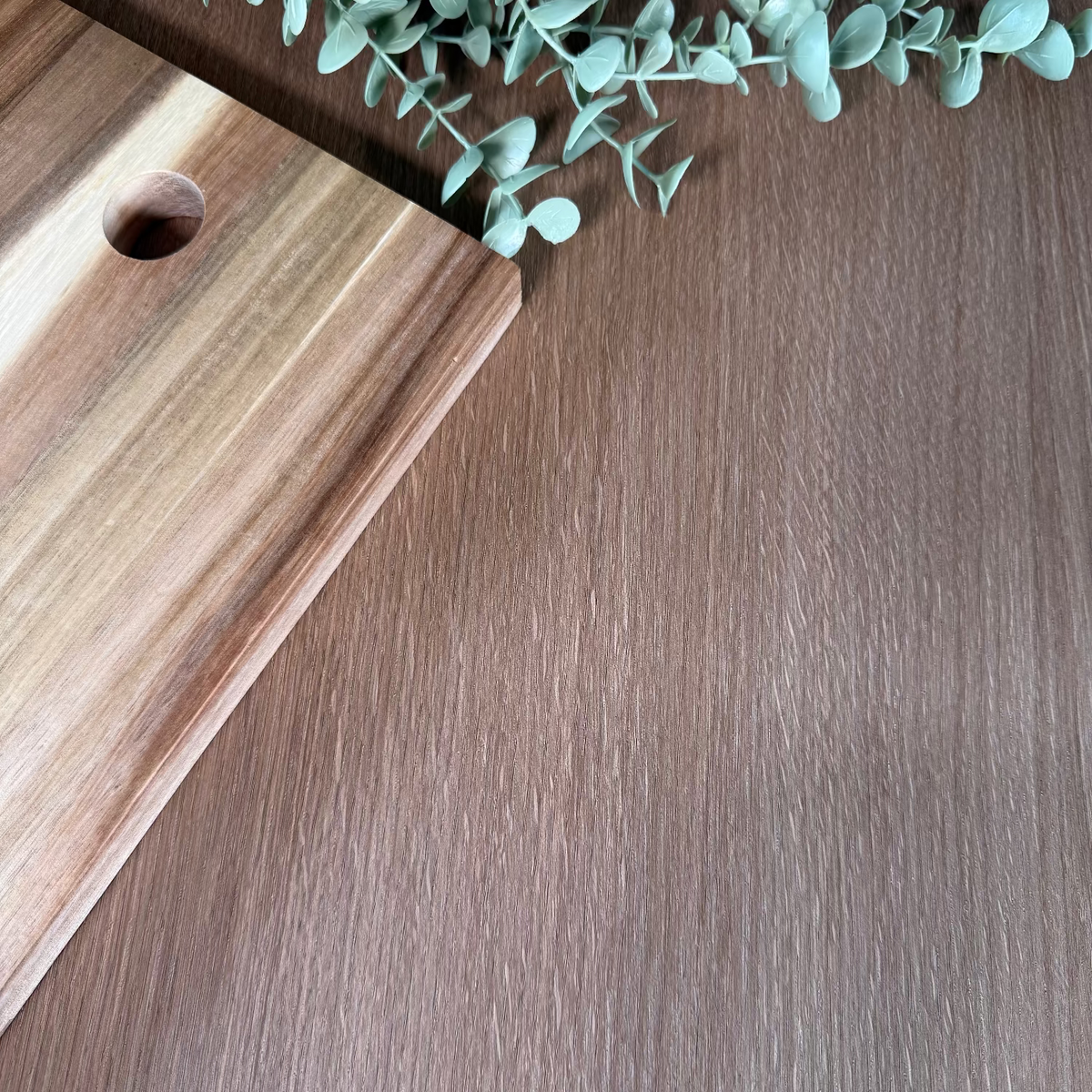 Wooden cutting board with a plant on a oak wood grain adhesive vinyl wrapped benchtop