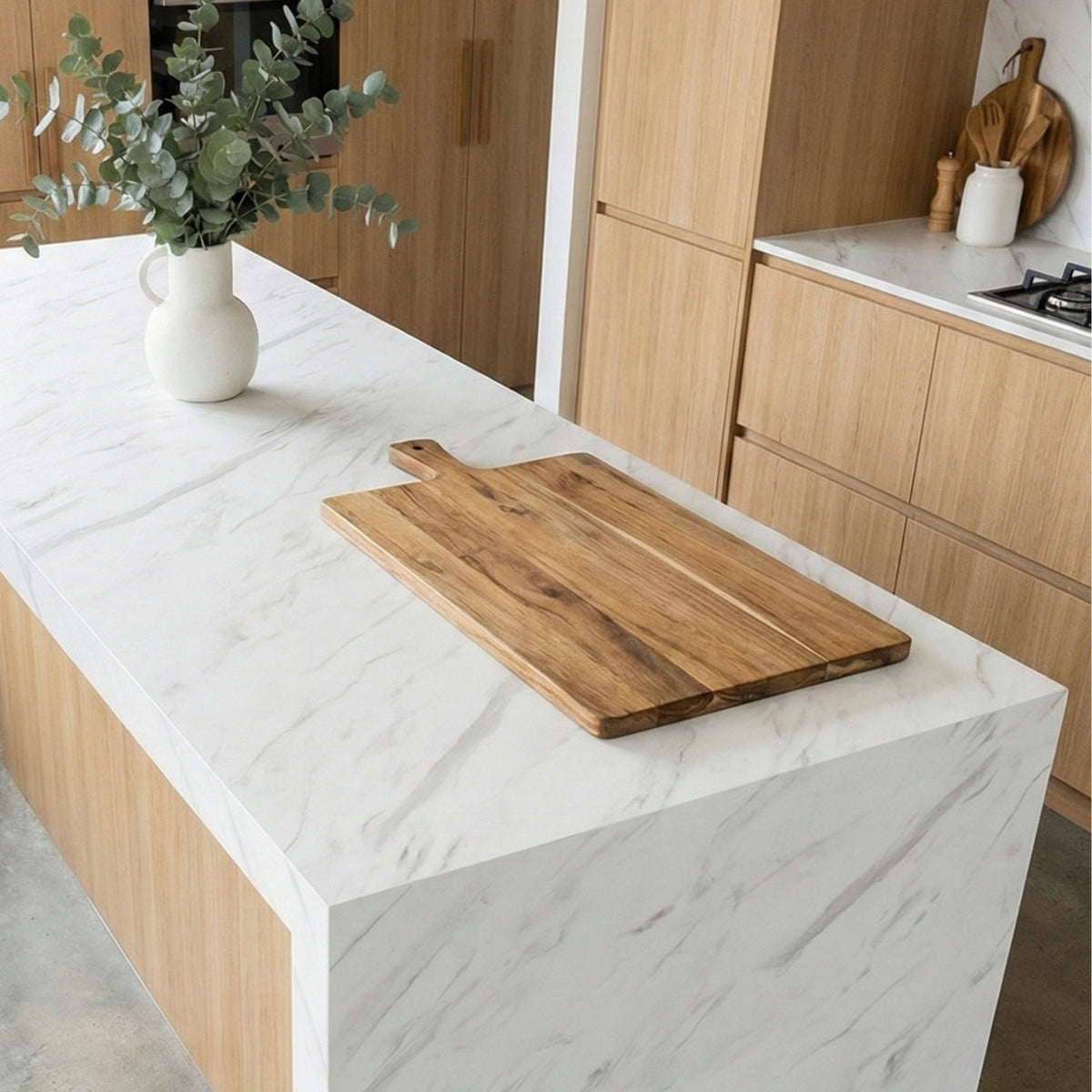 Wooden cutting board on a marble vinyl wrapped kitchen island with wooden cabinets in the background.