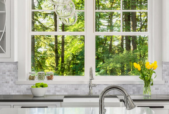 marble splashback tiles in kitchen window overlooking green forest