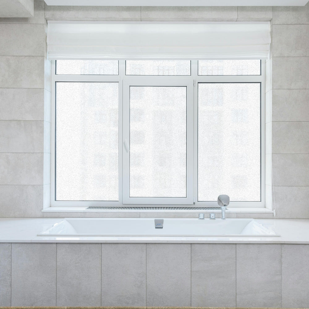 Bathroom with a window film covered window above a sink against a tiled wall.