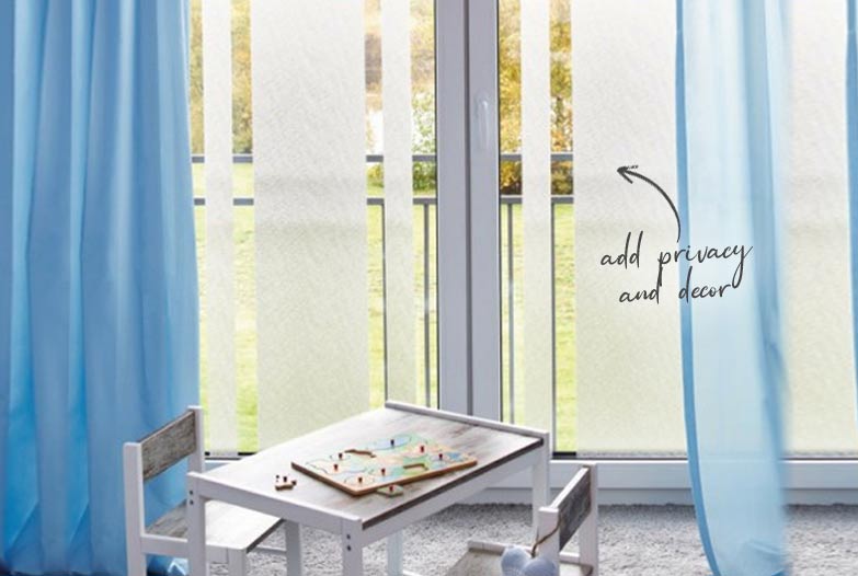Kids room with small table in the centre in front of large ranch slider with frosted window stripes and blue sheer curtains on each side
