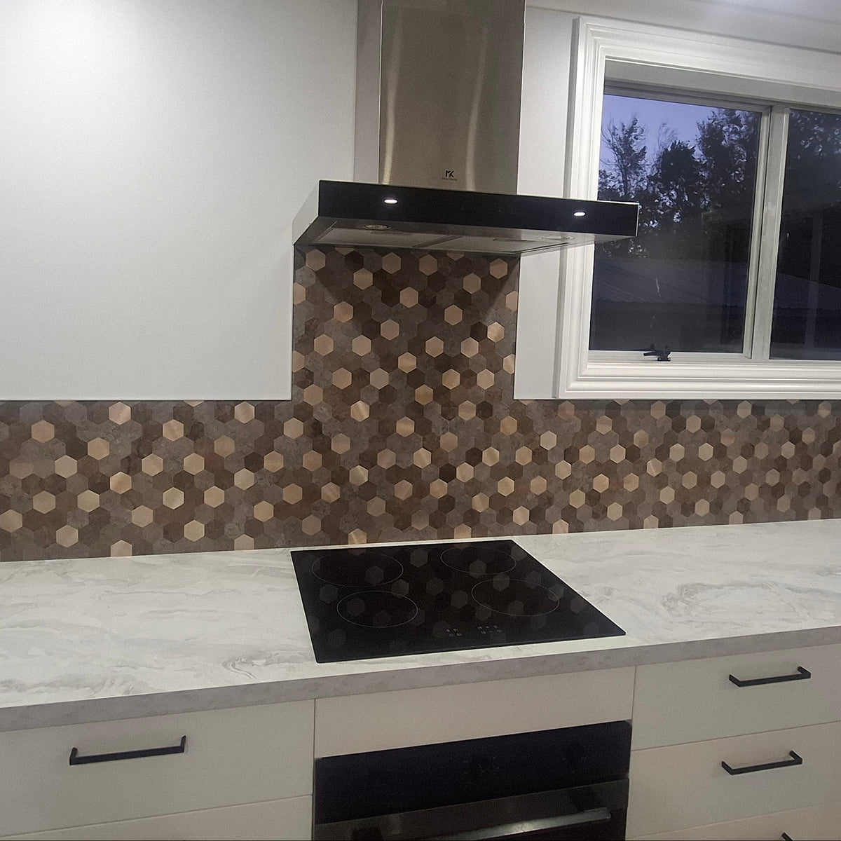 Modern kitchen with white cabinets, marble countertop, and patterned backsplash.