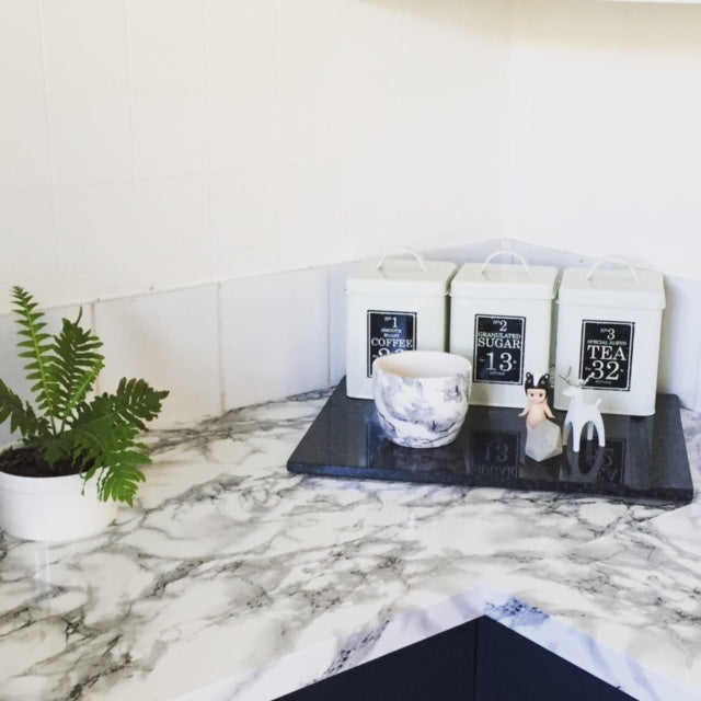 corner of marble white vinyl bench top displaying flower pot and tray