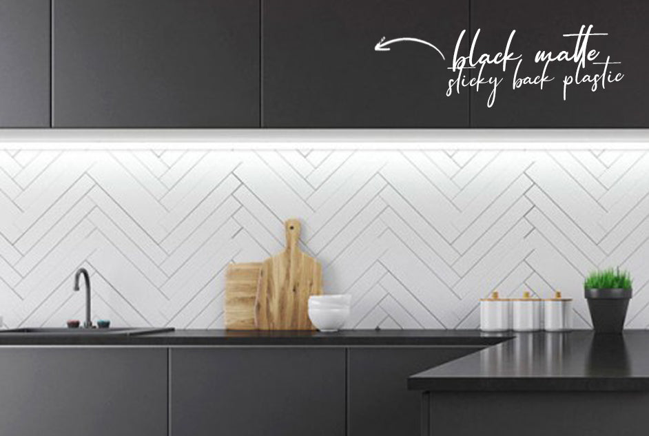 Kitchen cupboards wrapped in black matte sticky back plastic and white chevron tiles as splash back
