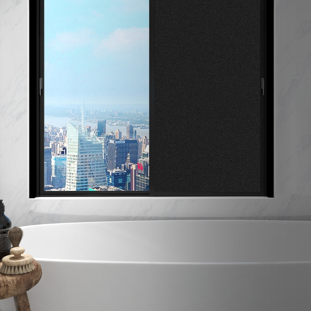Window with a cityscape view in a modern bathroom setting with one window covered with blackout window film.