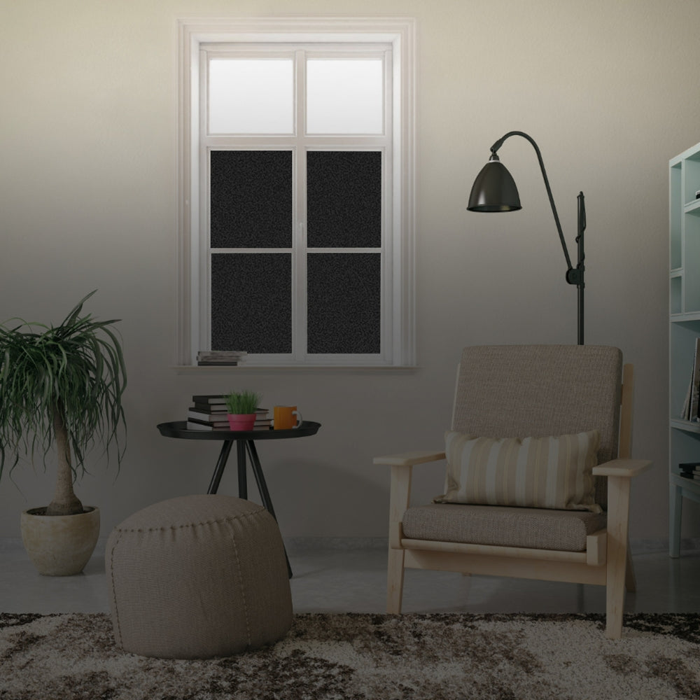 Living room with a beige armchair, ottoman, and small table near a window with blackout window film.