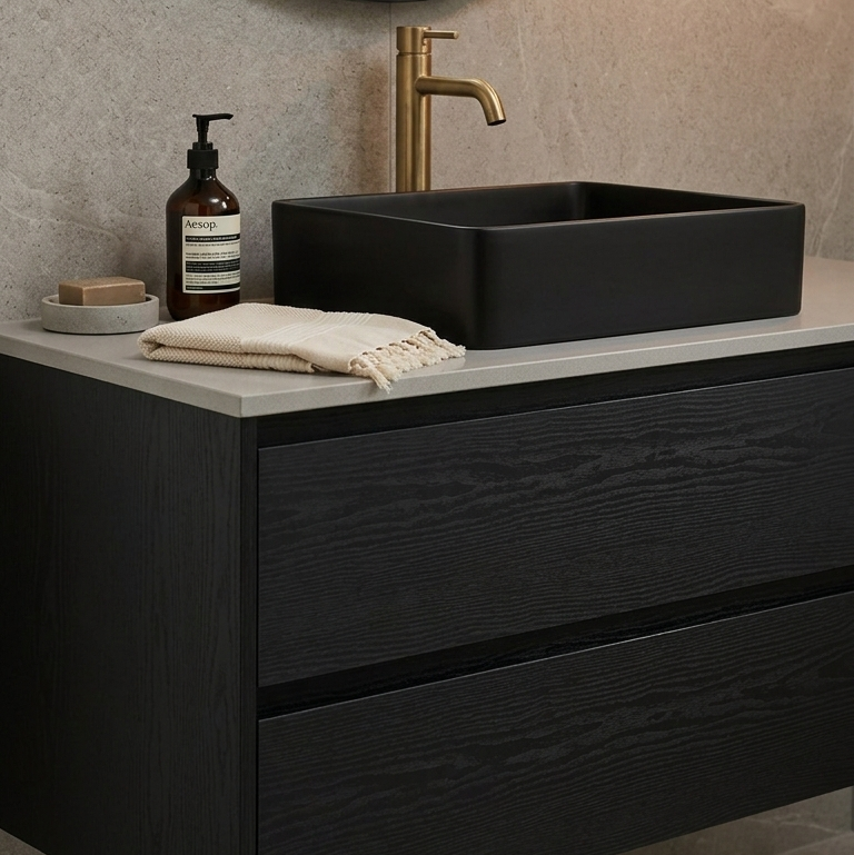 Bathroom vanity with black sink, gold faucet, and round mirror.
