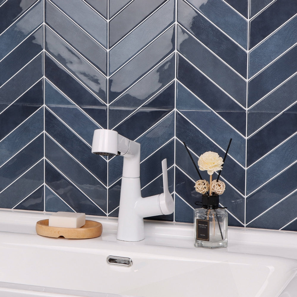 Modern bathroom sink setup with white faucet against a blue chevron tiled wall.