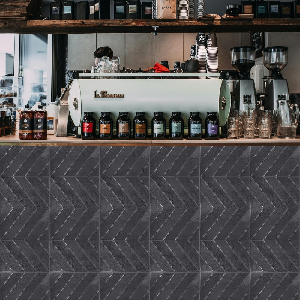 Coffee counter with La Marzocco machine and coffee beans, against a dark tiled wall.