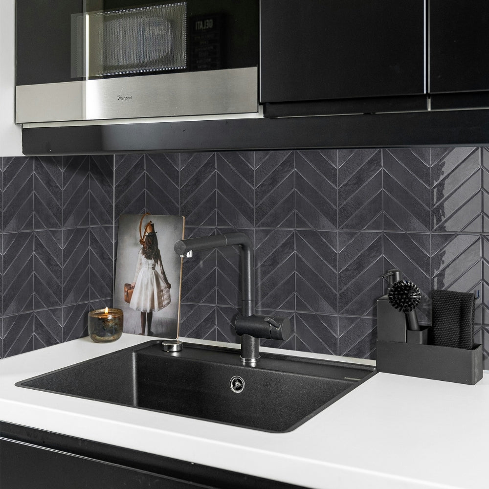 Modern kitchen with black sink, faucet, and chevron tiled wall.