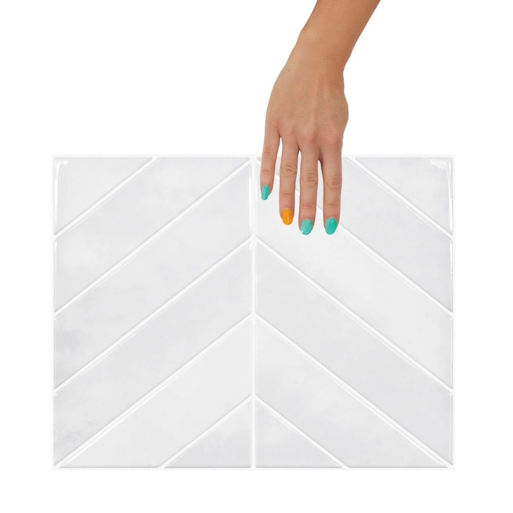 White chevron-patterned tile with a hand touching it on a white background