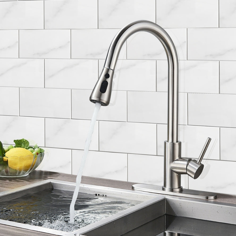 Modern kitchen faucet with water flowing into a sink against a marble tiled wall.