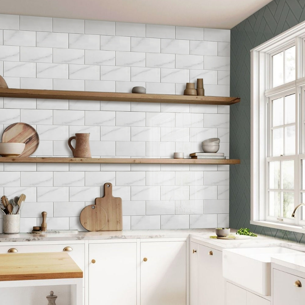 Modern kitchen with white marble tiled wall, wooden shelves, and natural light.