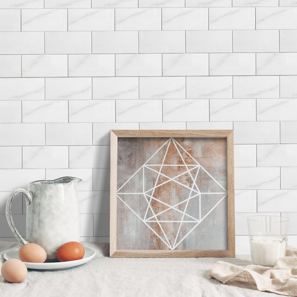 Framed geometric art piece on a kitchen counter with a marble tiled wall background