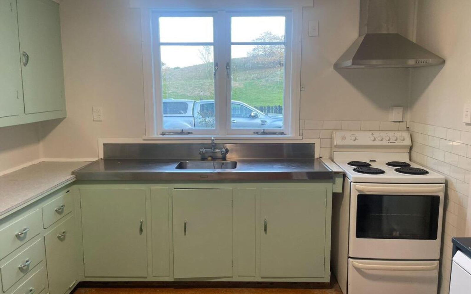 Kitchen with green cabinets, white stove and tiles and window view