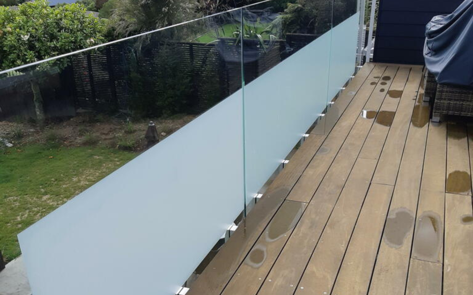 Wooden deck with glass railing with windoverlooking a gardenw film