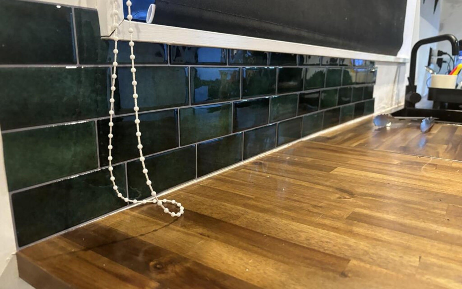Green tiled wall with a wooden benchtop
