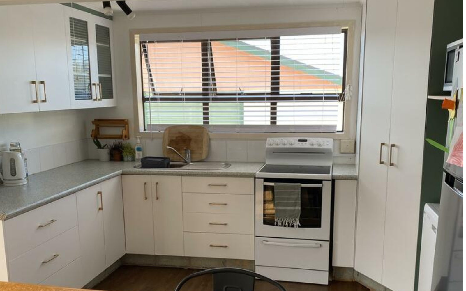 Modern kitchen with white vinyl wrapped cabinets, appliances, and a window.