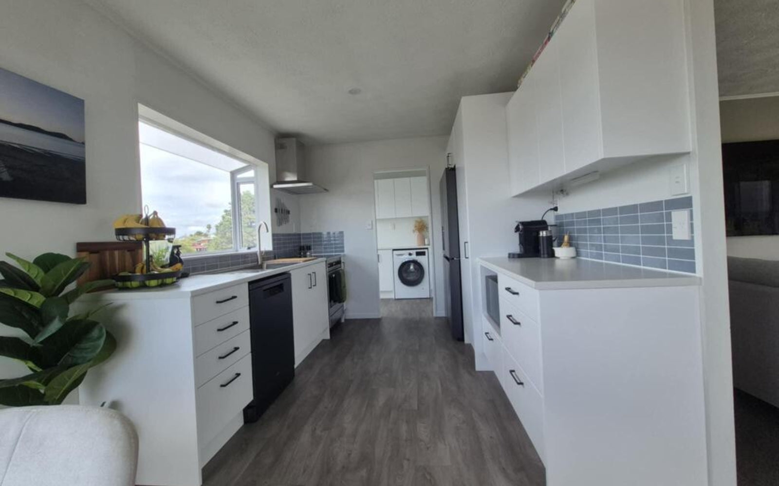 Modern kitchen with white cabinets and appliances, and blue tiles splashback