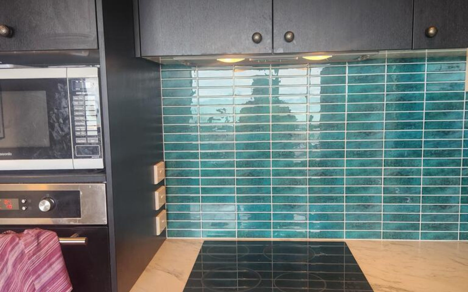 Kitchen with black appliances and green tiled wall