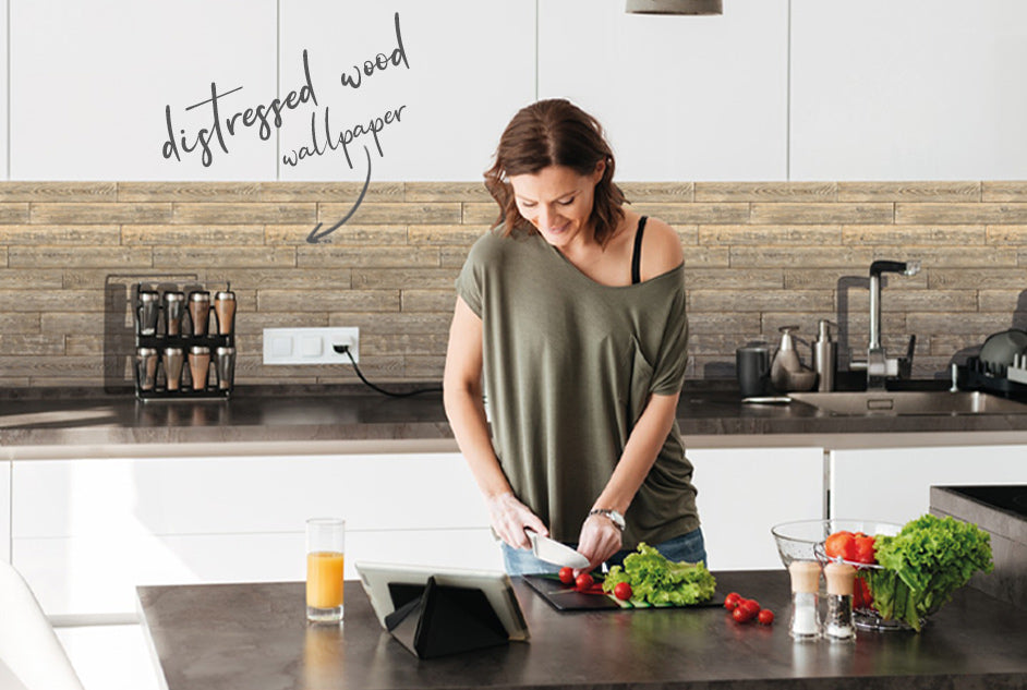 woman chopping vegetables in whit kitchen with distressed wallpaper as a splashback