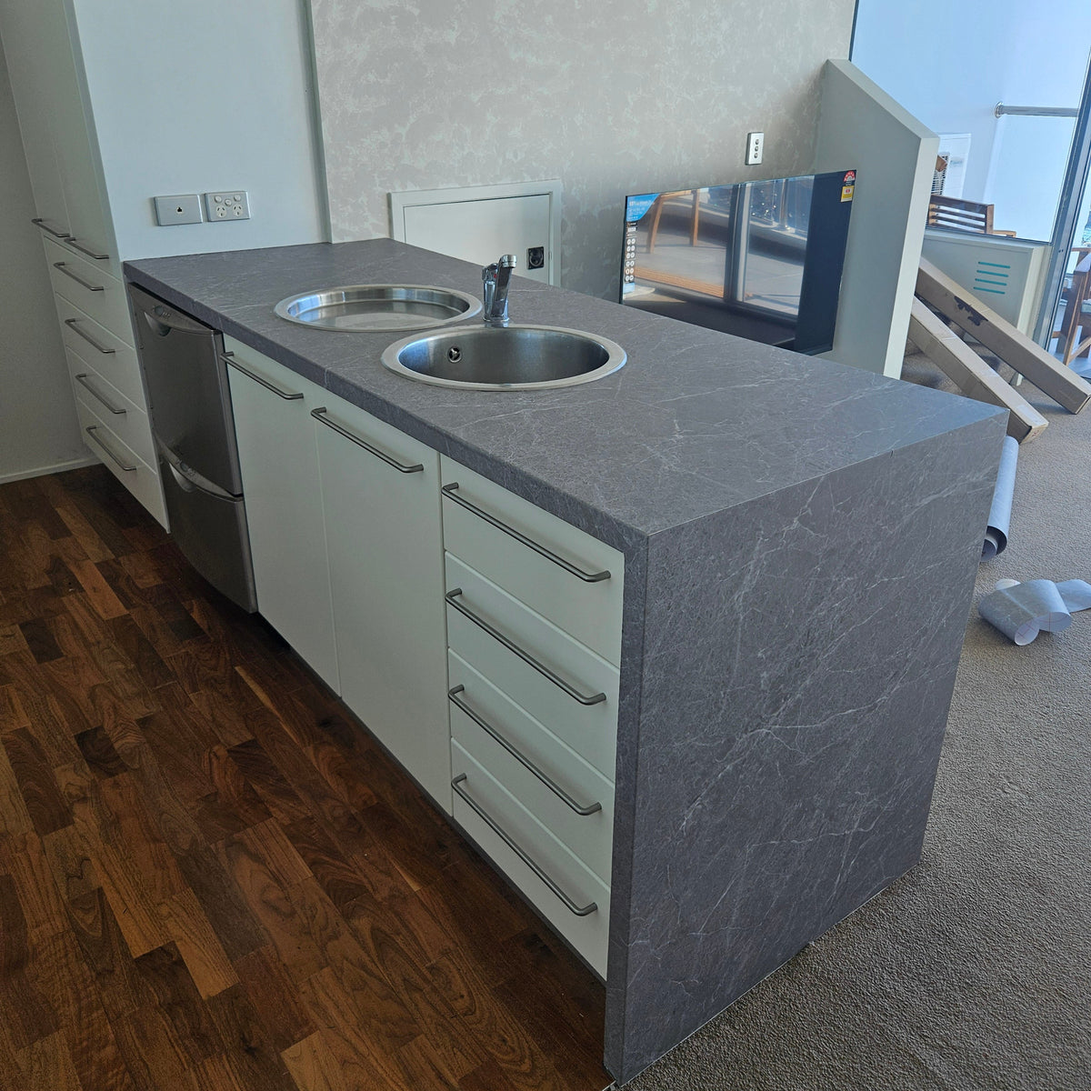 Modern kitchen island with grey countertop and stainless steel sink