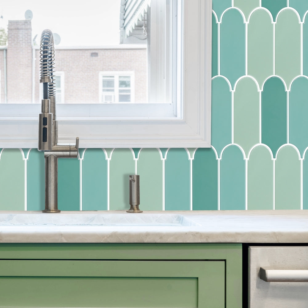 Kitchen sink with green tiles and a window above the sink.