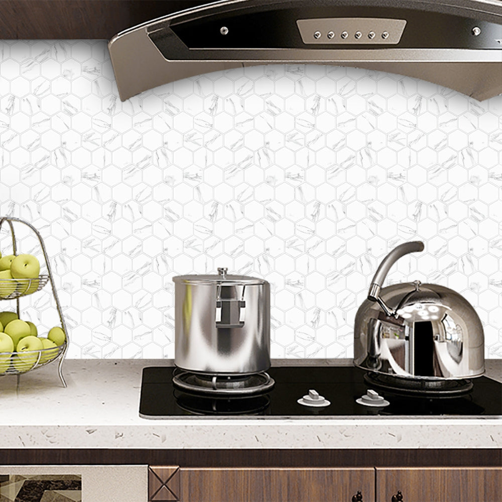 Kitchen setup with a stove, pots, and a kettle against a white marble tiled wall.