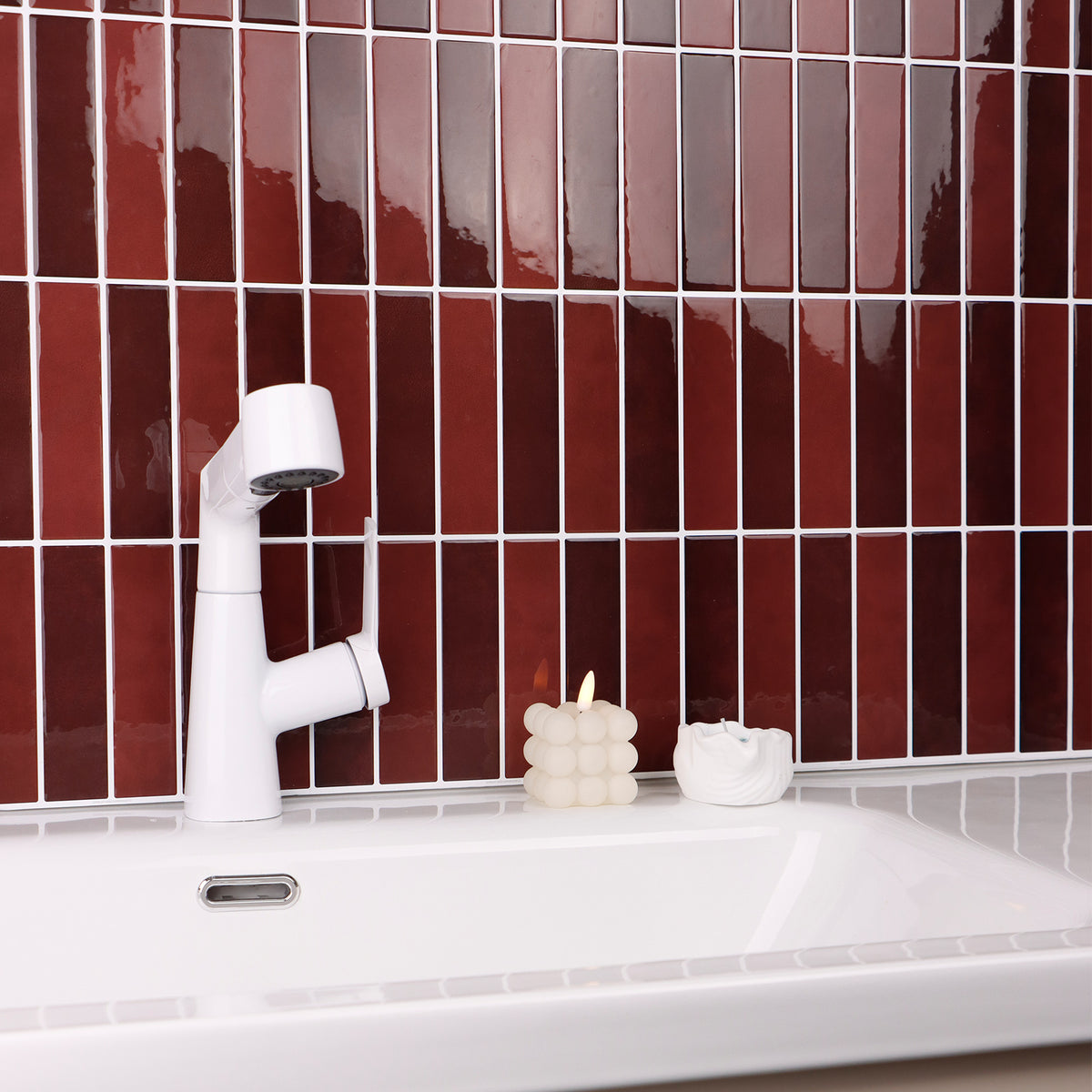 White bathroom faucet on a white sink with red tiled wall
