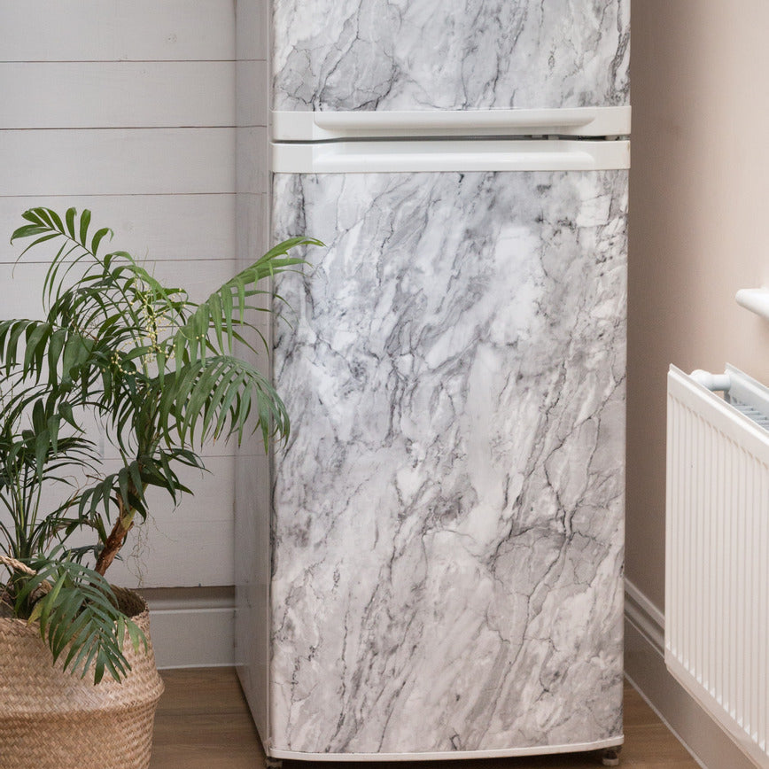 Fridge with marble design wrap in a room with plants and a radiator.