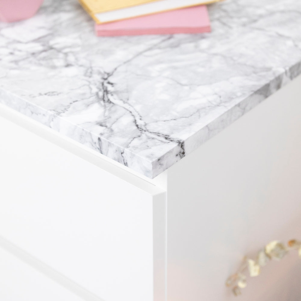 Marble-patterned surface with a pink and gold object on a white background