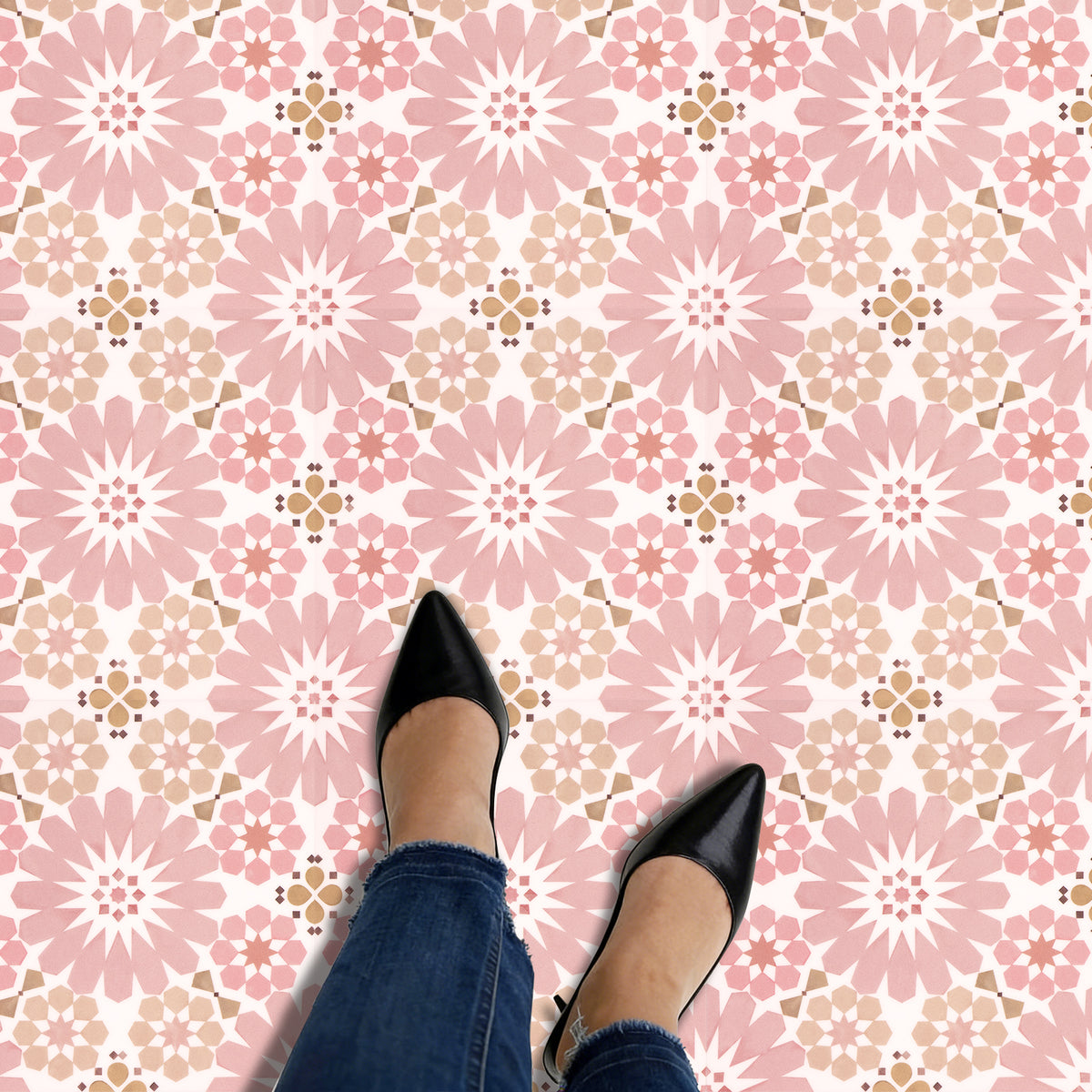 Black shoes and blue jeans on a pink floral patterned floor.