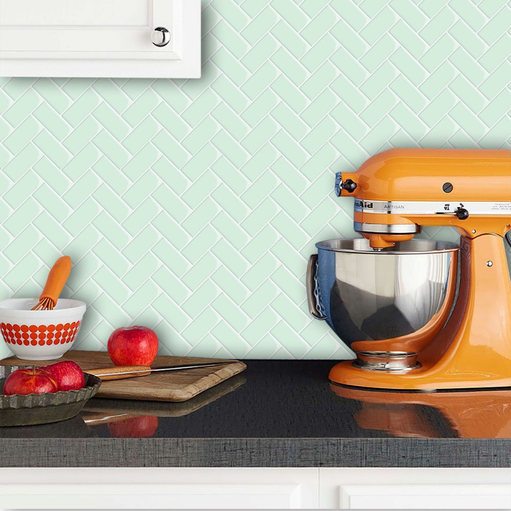 Orange stand mixer on a kitchen counter with a green tiled wall in the background