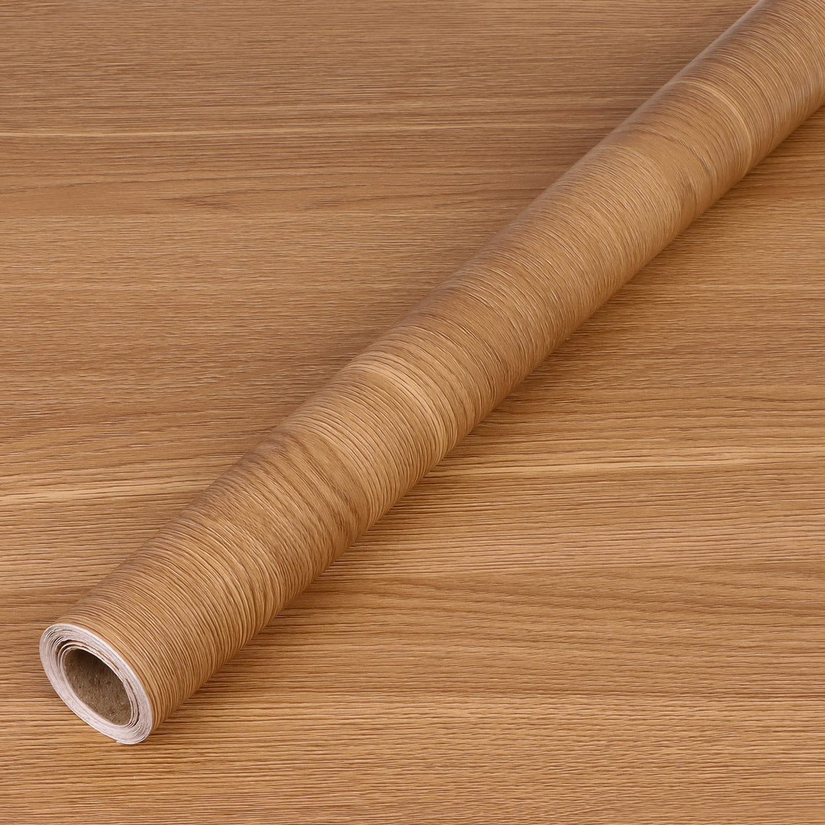 Roll of wood-patterned adhesive vinyl on a wooden surface