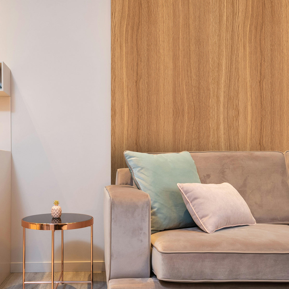Beige sofa with decorative pillows against a wooden wall