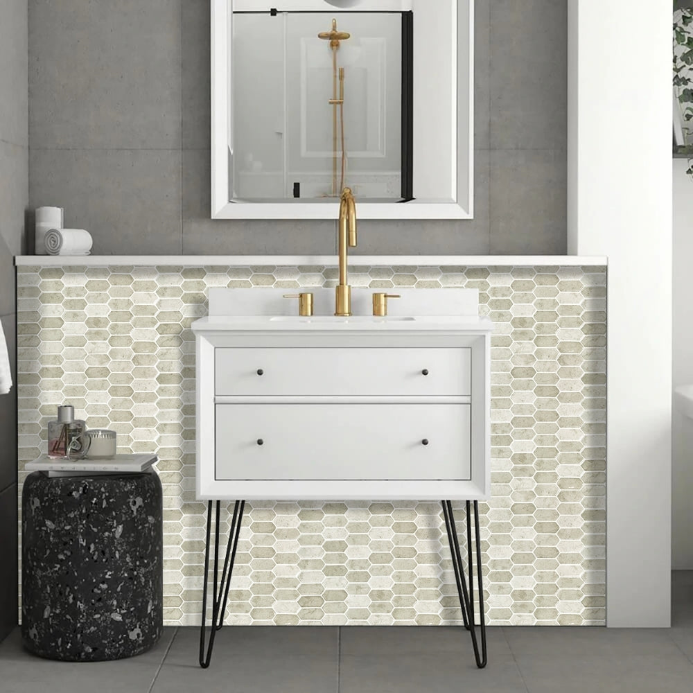 Bathroom vanity with white cabinet, gold fixtures, and mosaic tile backsplash.