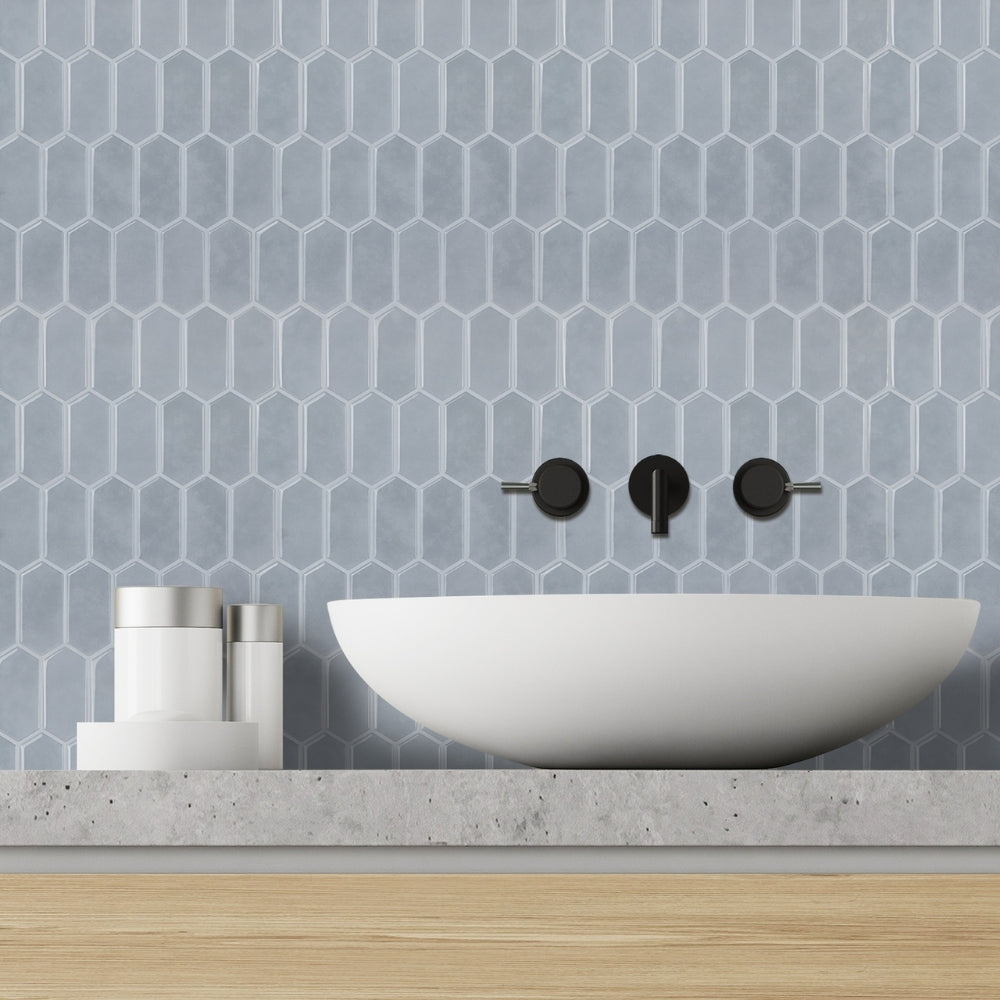 Bathroom vanity with a white sink, blue hexagonal tiles on the wall, and black faucet.