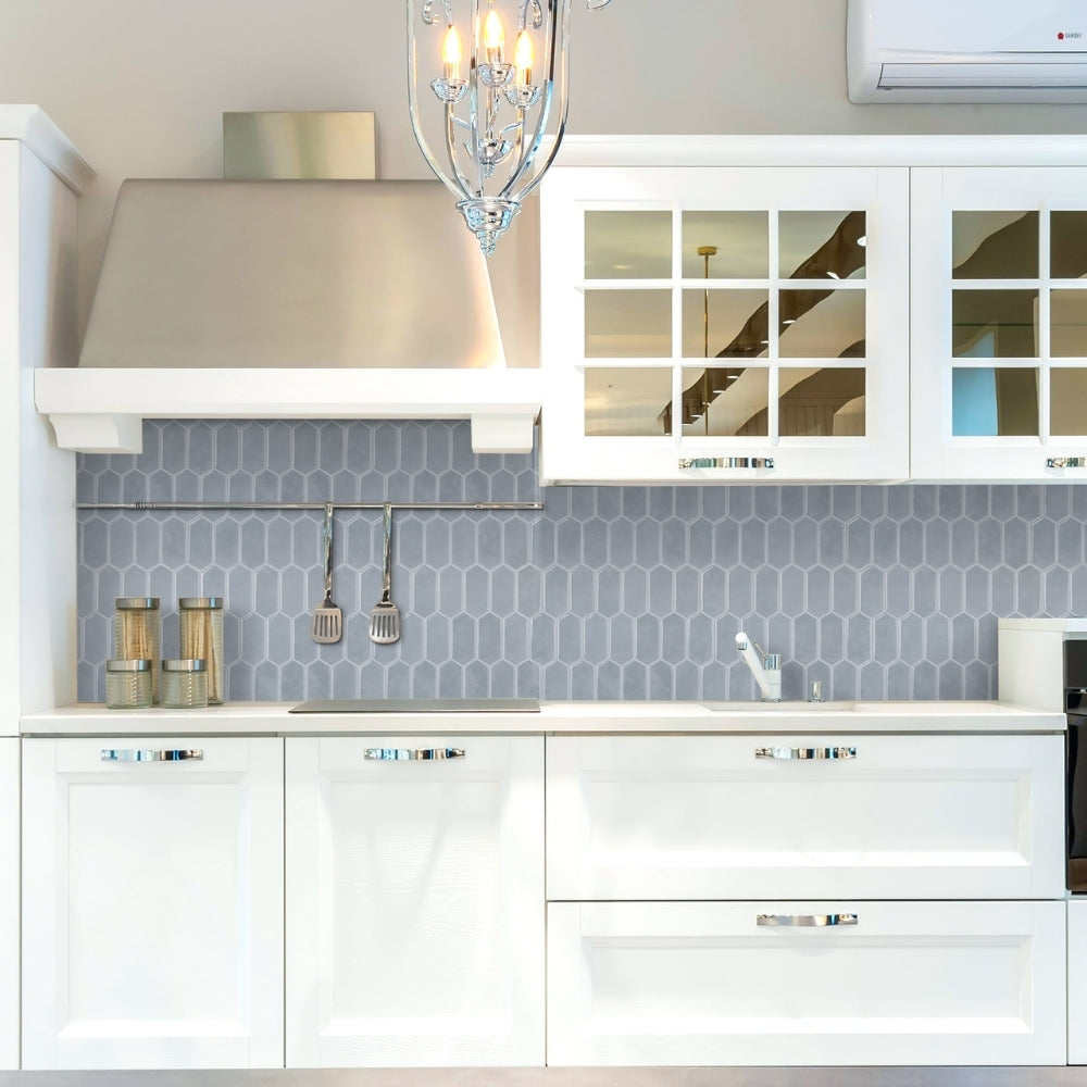 Modern kitchen with white cabinets, grey-blue backsplash, and stainless steel range hood.