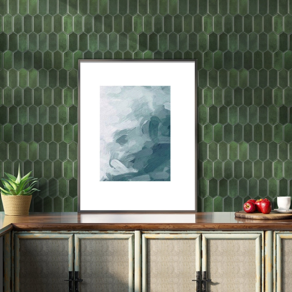 Framed abstract art on a green tiled wall with a wooden cabinet below.