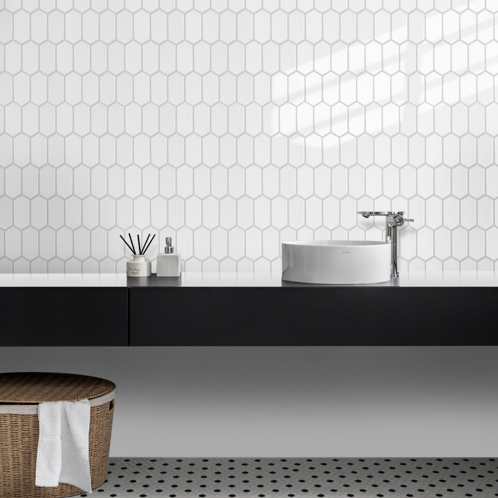 Bathroom with hexagonal white tiles on the wall, black countertop, and wooden basket.