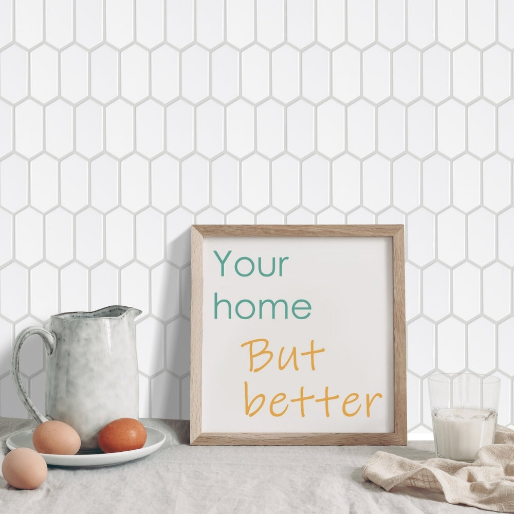 Framed print with &#39;Your home But better&#39; text on a kitchen counter with eggs and a pitcher.