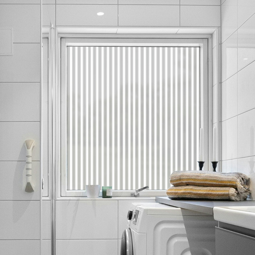 Bathroom with a window covered by reeded window film, towels on a counter, and a washing machine.