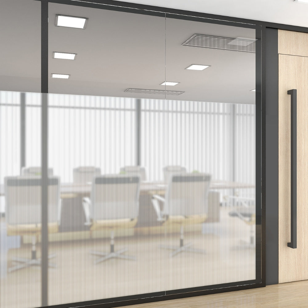 Glass office door with reeded window film with a view into a conference room with chairs and tables.