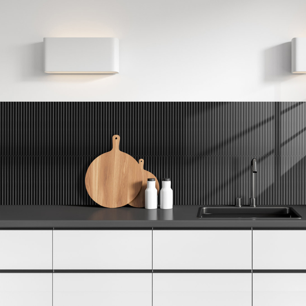 Modern kitchen with black countertop and black reeded tiles, white cabinets, and wooden cutting board.