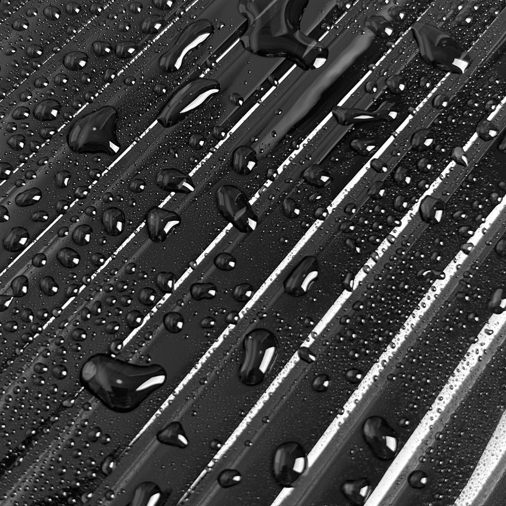 Close-up of a black reeded tiles with water droplets on a textured surface
